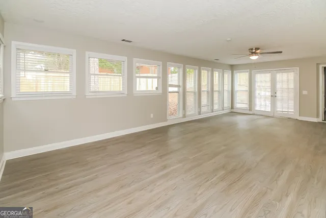 a view of an empty room with wooden floor and a window