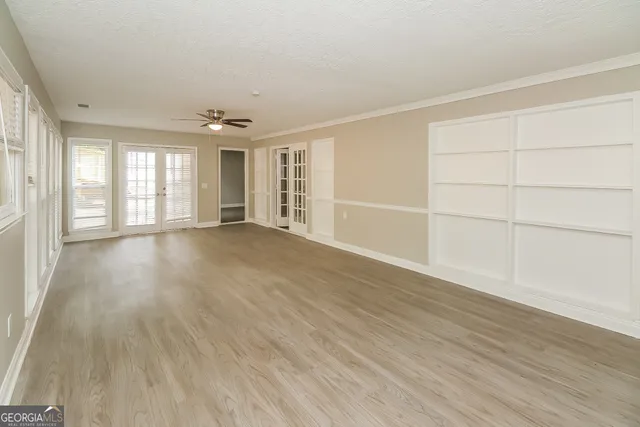 an empty room with wooden floor and windows