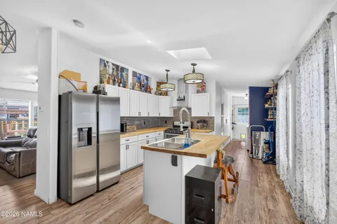 a kitchen with stainless steel appliances granite countertop a refrigerator a sink dishwasher a stove and a dining table with wooden floor