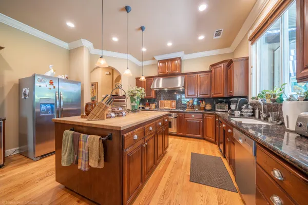 a kitchen with stainless steel appliances granite countertop a sink a stove and a refrigerator