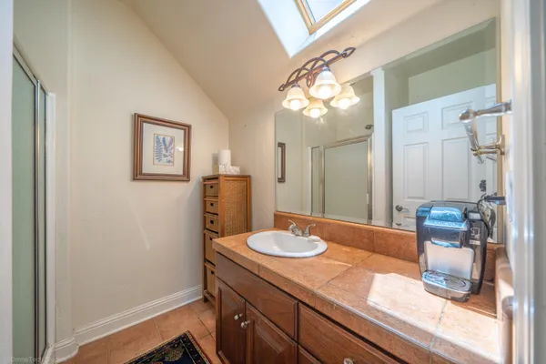 a bathroom with a granite countertop sink a mirror and a shower