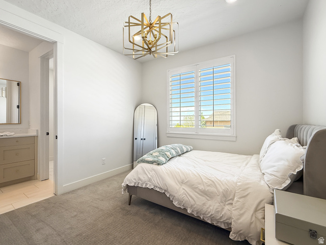 916 Rocky Mountain Way Elk Ridge, UT 84651 - Photo 29 of 54 Bedroom with light carpet, a chandelier, light tile patterned flooring, and a textured ceiling
