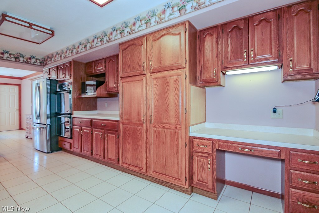 6475 Taylor Road Painesville, OH 44077 - Photo 7 of 23 Kitchen featuring extensive wood cabinetry, light-toned countertops, and tile flooring