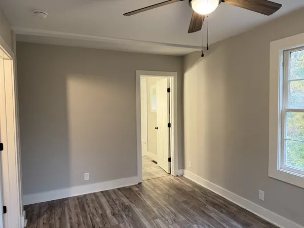 a view of an empty room with window and chandelier fan