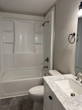 a bathroom with a granite countertop sink a toilet and shower