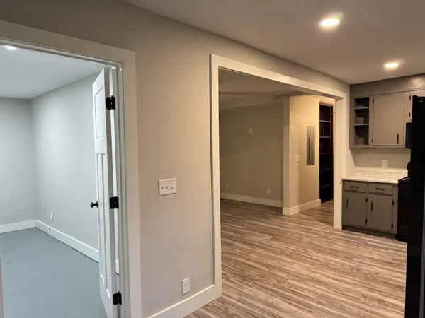 a view of a hallway with a kitchen space with wooden floor and cabinets