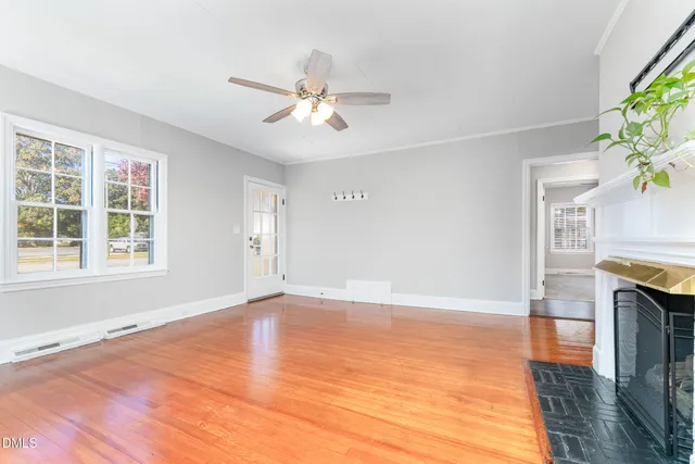 an empty room with wooden floor fireplace and windows