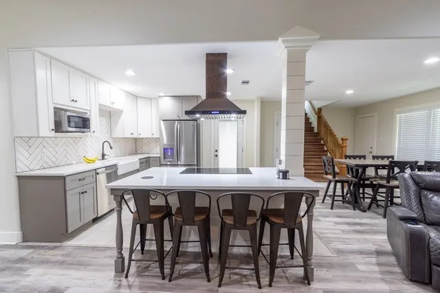 a kitchen with stainless steel appliances kitchen island granite countertop a dining table chairs and sink