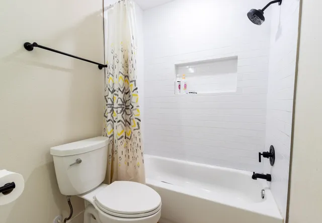 a white toilet sitting next to a bath tub and shower