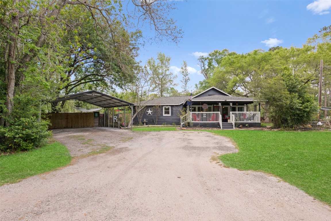 Charming country ranch with inviting front porch, mature trees, and covered parking.