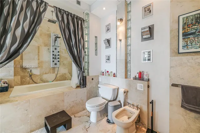 a white toilet sitting next to a bathroom sink and a shower