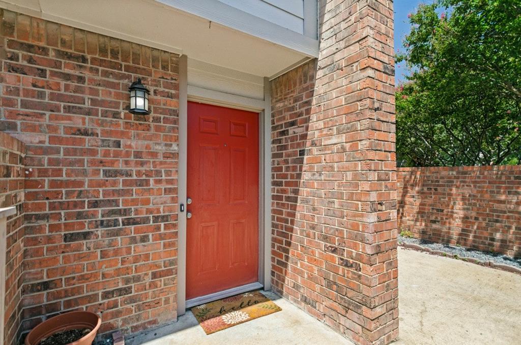 18240 Midway Road, Unit 905 Dallas, TX 75287 - Photo 4 of 29 Brick exterior with a red paneled entry door, covered porch, and exterior wall lantern