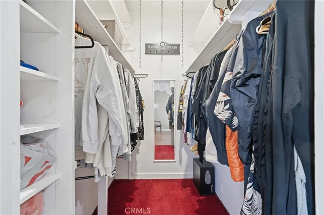 a view of walk in closet with clothes and shoes