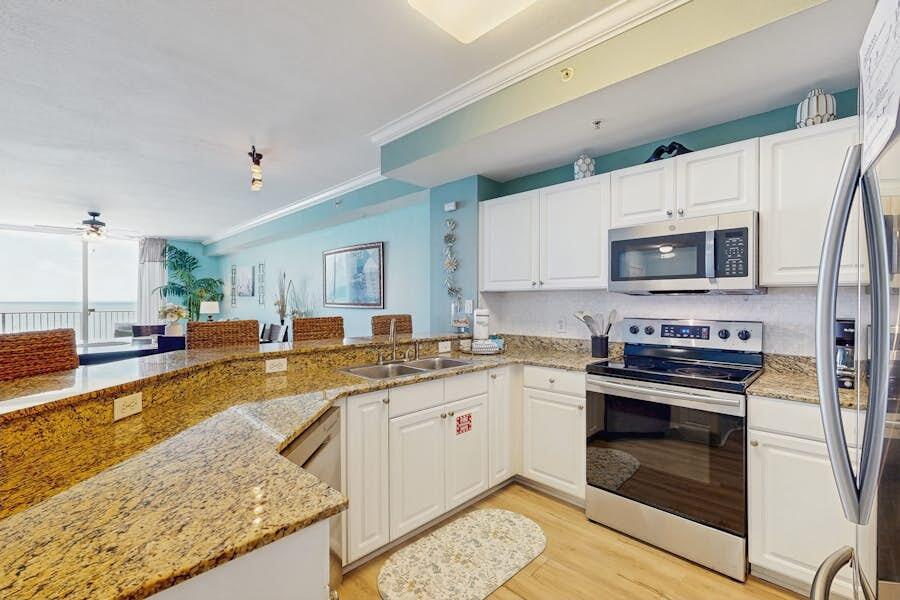 16819 Front Beach Road, Unit 602 Panama City Beach, FL 32413 - Photo 9 of 53 a kitchen with stainless steel appliances granite countertop a stove a sink and a microwave