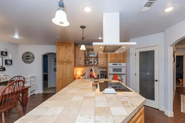 a living room with stainless steel appliances kitchen island granite countertop furniture and a chandelier