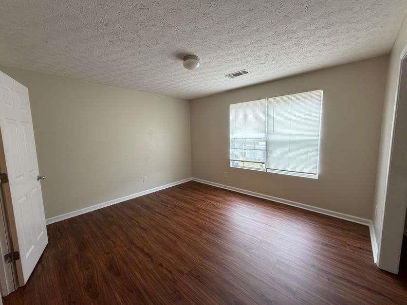 5196 Tew Lane Southwest Covington, GA 30014 - Photo 23 of 41 an empty room with wooden floor and windows