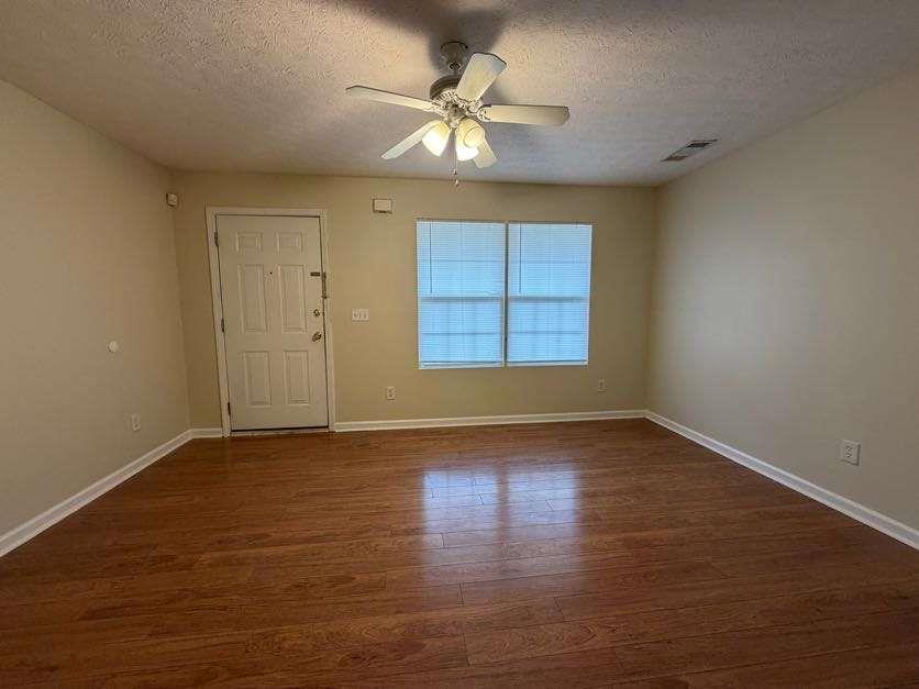 5196 Tew Lane Southwest Covington, GA 30014 - Photo 3 of 41 an empty room with wooden floor chandelier fan and windows