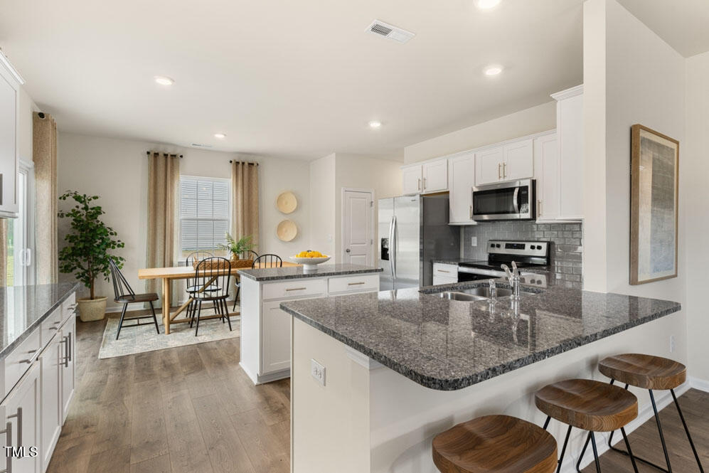 a kitchen with granite countertop kitchen island stainless steel appliances a sink a counter top space cabinets and living room view