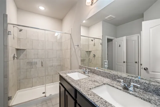 a bathroom with a granite countertop sink a mirror and shower