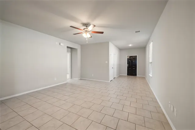 a view of an empty room and chandelier fan
