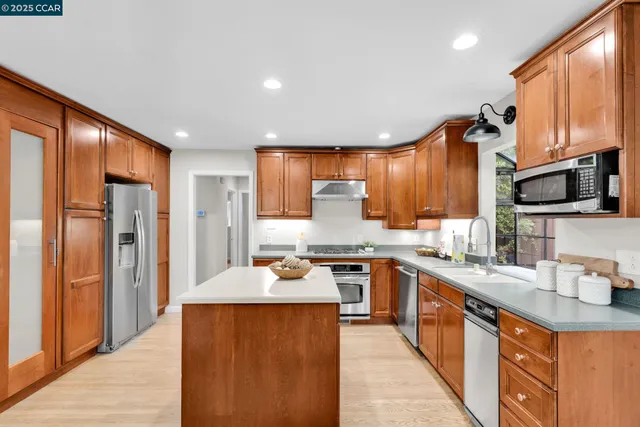 a kitchen with stainless steel appliances granite countertop sink stove refrigerator and cabinets