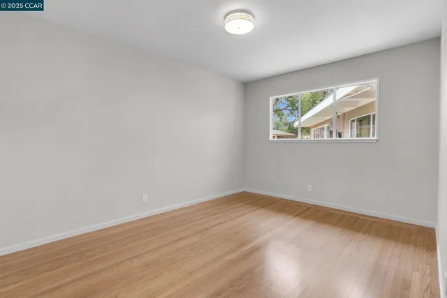 an empty room with wooden floor and window