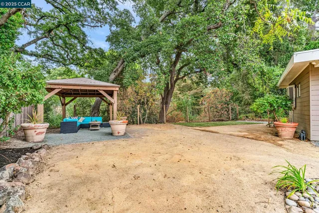 a view of a yard with table and chairs under an umbrella