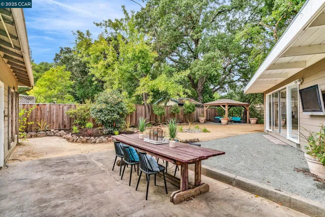 a view of a patio with table and chairs and potted plants with wooden floor and fence