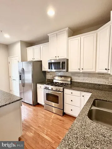 a kitchen with granite countertop a refrigerator sink and microwave