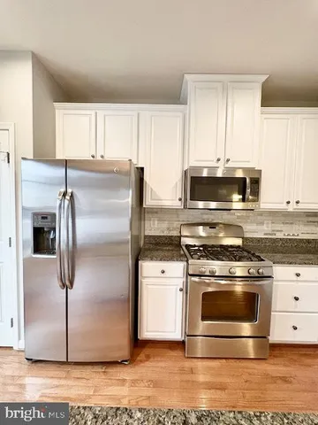 a kitchen with stainless steel appliances granite countertop a stove a refrigerator and a microwave