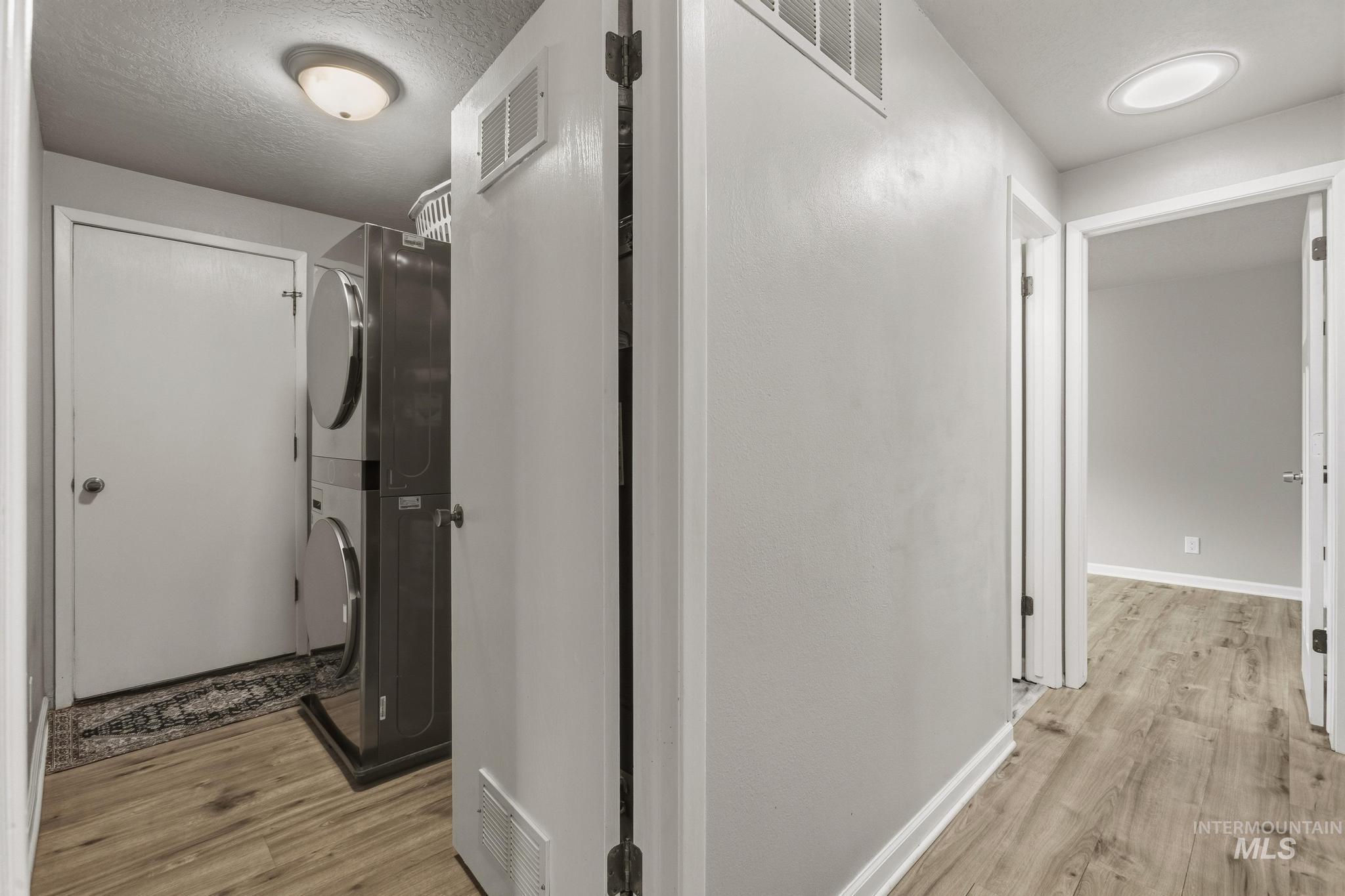 3040 West Hester Street Boise, ID 83702 - Photo 11 of 20 Dedicated laundry area featuring a stacked washer and dryer, wood-finish flooring, and white baseboards