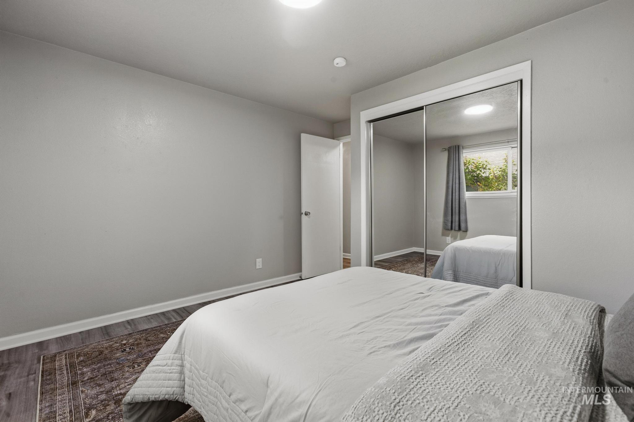 3040 West Hester Street Boise, ID 83702 - Photo 13 of 20 Room featuring light gray walls, wood-finish flooring, and a mirrored closet with sliding doors