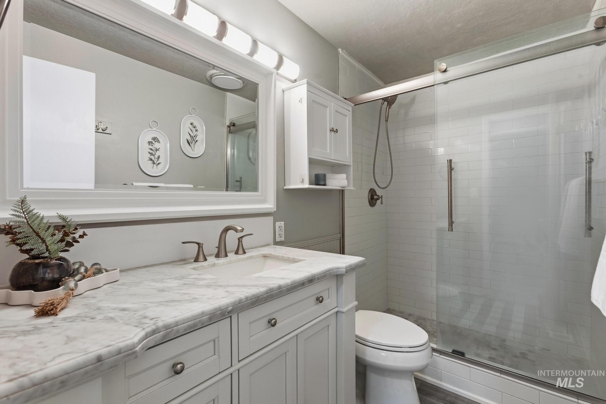 3040 West Hester Street Boise, ID 83702 - Photo 14 of 20 Vanity with a stone countertop and integrated sink, complemented by a large framed mirror with overhead lighting