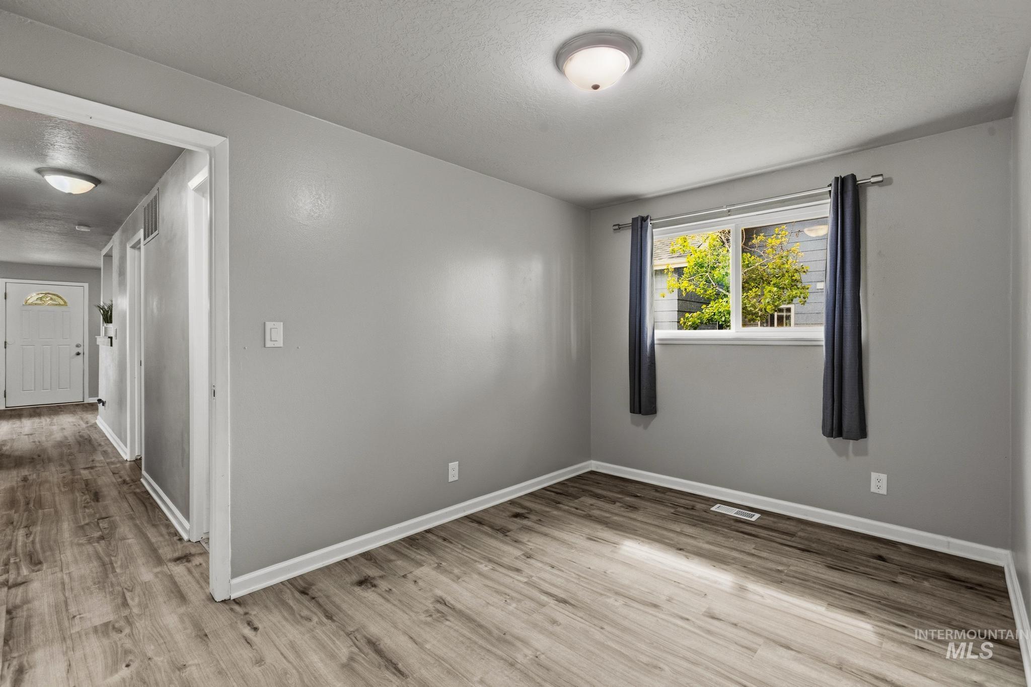 3040 West Hester Street Boise, ID 83702 - Photo 15 of 20 Spacious room with light gray walls, wood-finish flooring, and white baseboards