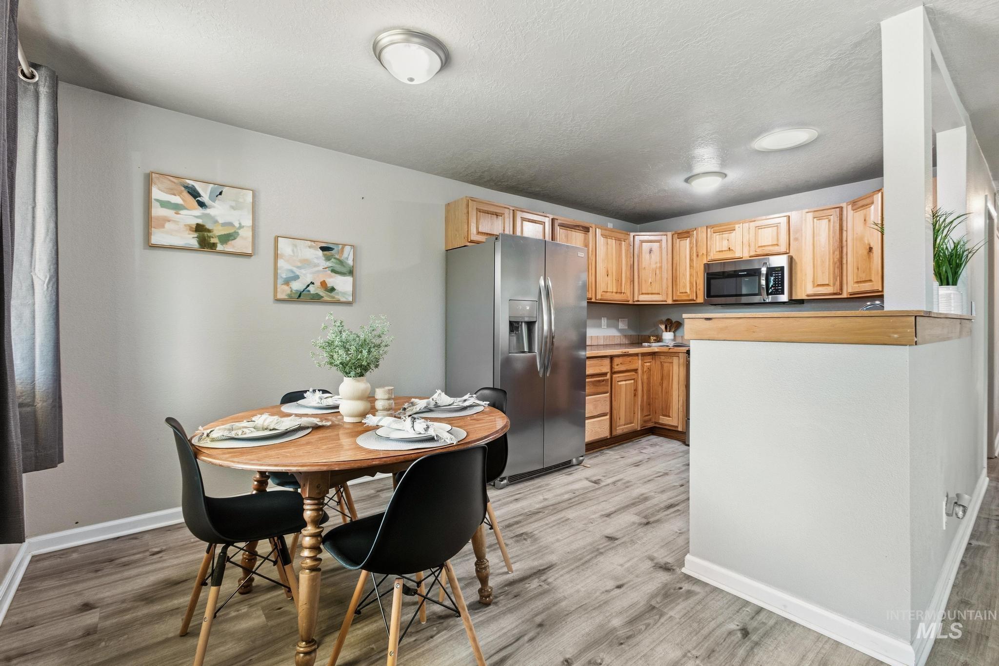 3040 West Hester Street Boise, ID 83702 - Photo 6 of 20 Kitchen with wood-finish flooring featuring light wood cabinetry, stainless steel appliances, and a half-wall partition