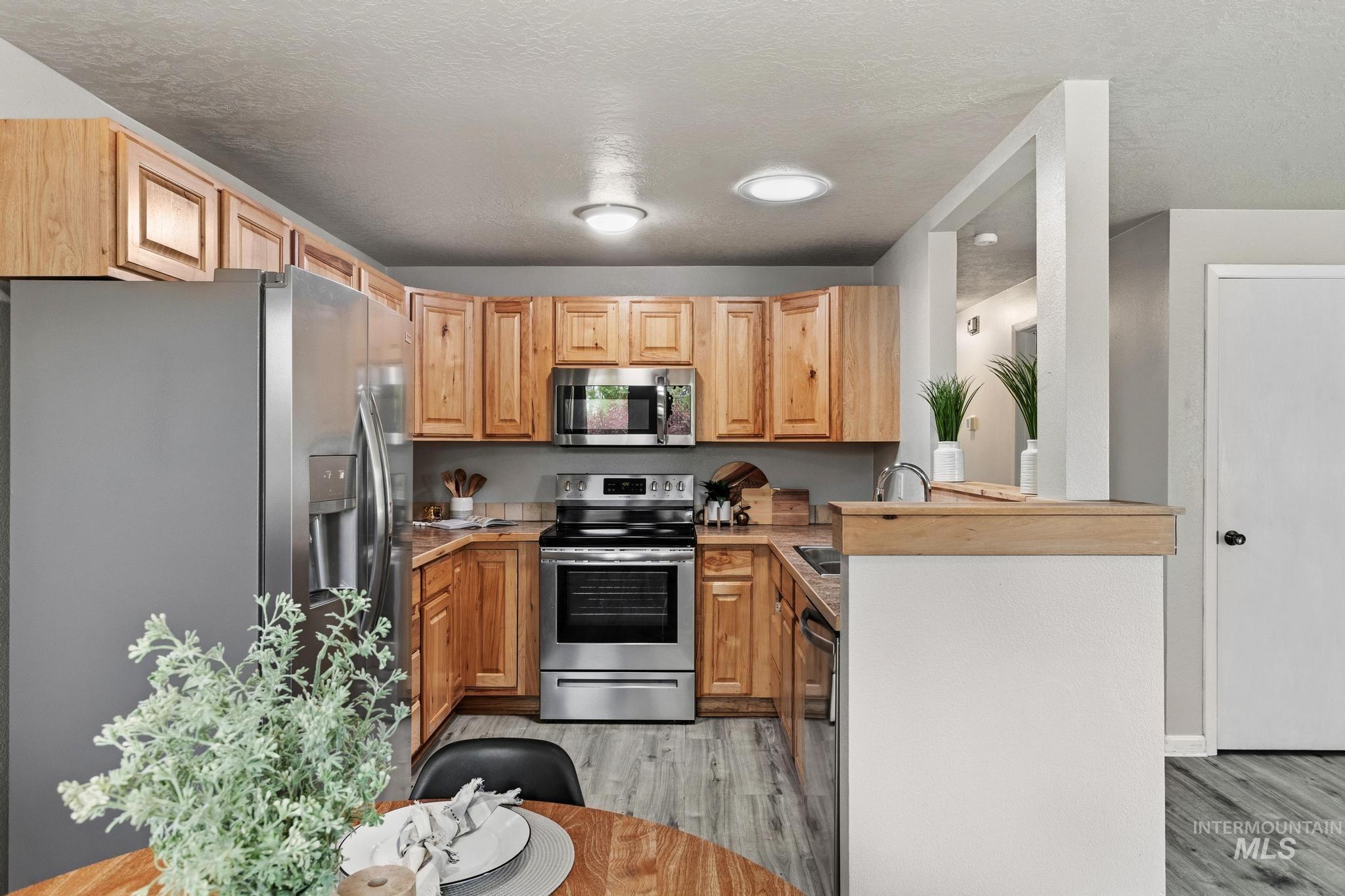 3040 West Hester Street Boise, ID 83702 - Photo 7 of 20 U-shaped kitchen featuring wood cabinetry, stainless steel appliances, wood-finish flooring, and recessed lighting