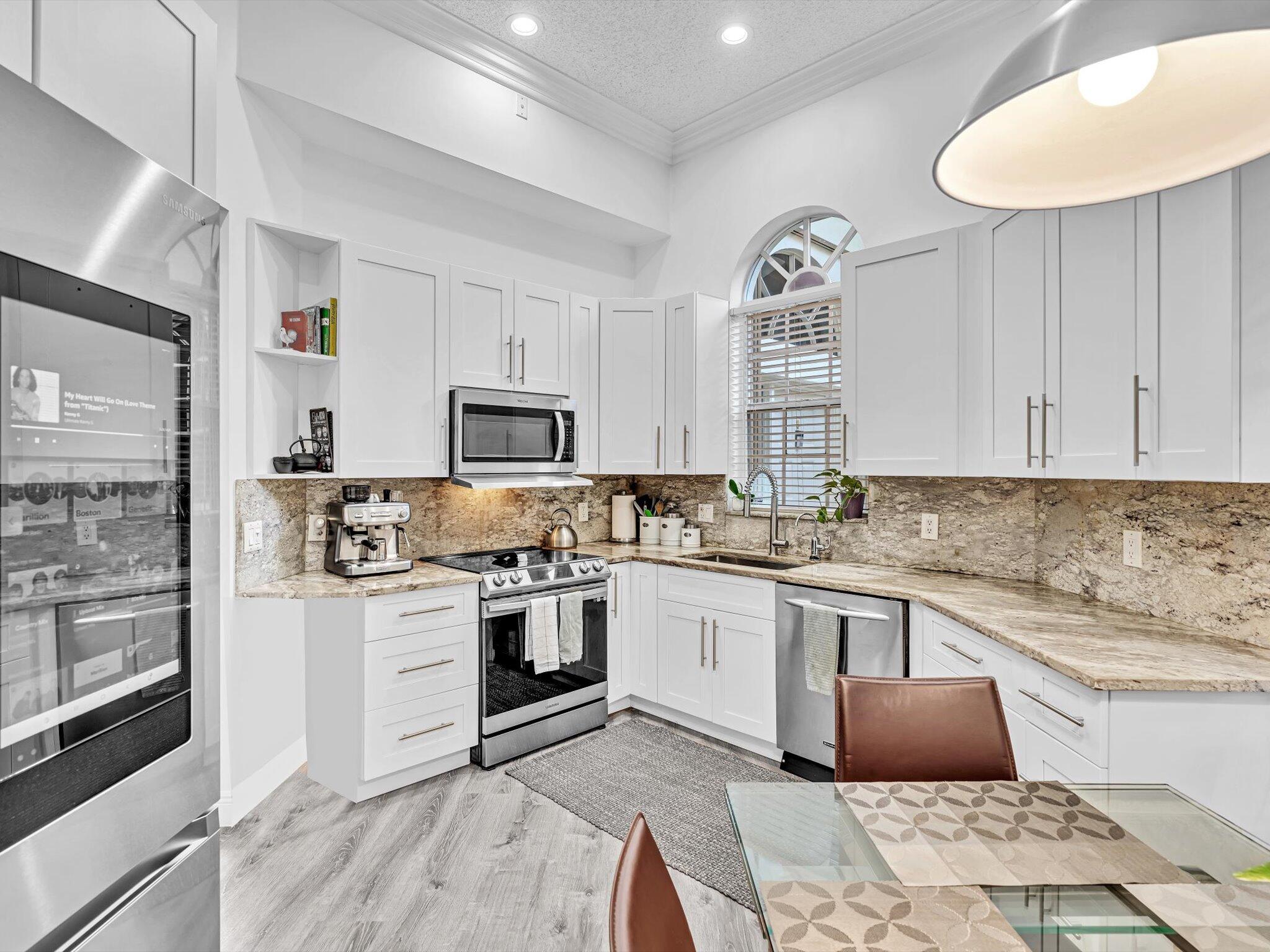 2486 Northwest 66th Drive Boca Raton, FL 33496 - Photo 31 of 80 a kitchen with stainless steel appliances granite countertop a stove top oven a sink and dishwasher with white cabinets
