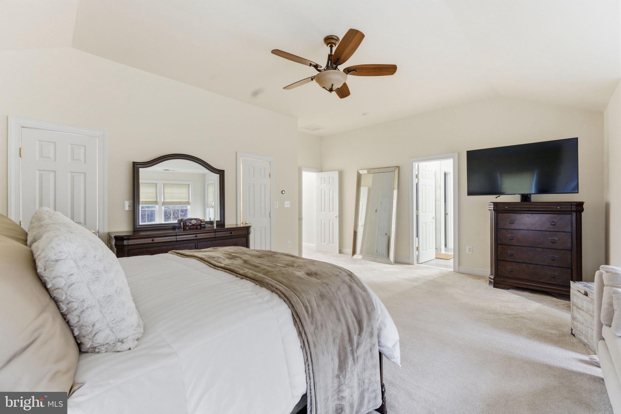 7669 Oak Field Court Springfield, VA 22153 - Photo 27 of 57 a bedroom with a bed a large mirror and a flat tv screen on dresser