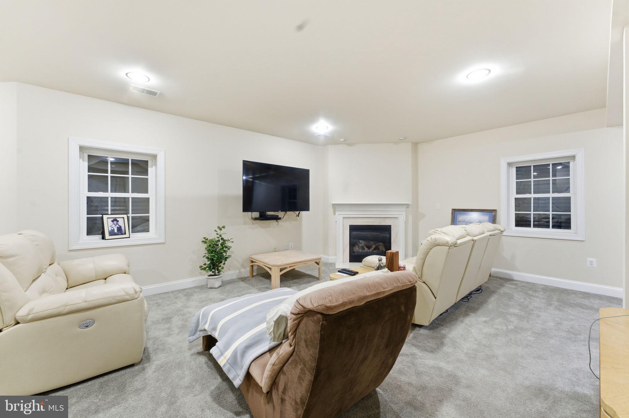 7669 Oak Field Court Springfield, VA 22153 - Photo 47 of 57 a living room with furniture a fireplace and a flat screen tv