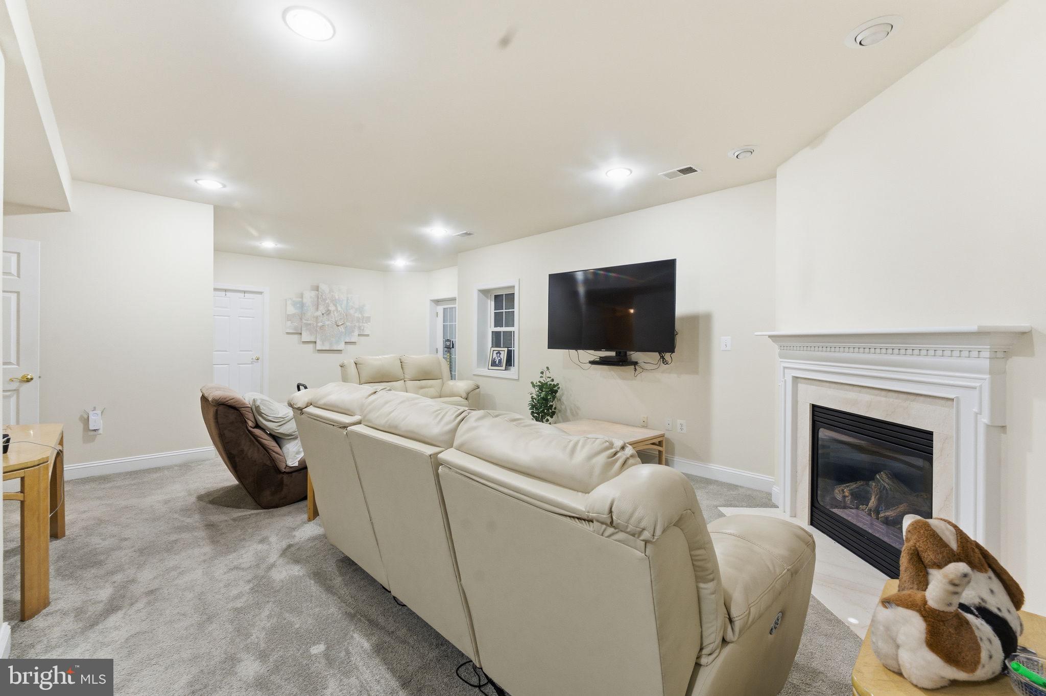 7669 Oak Field Court Springfield, VA 22153 - Photo 48 of 57 a living room with furniture a fireplace and a flat screen tv