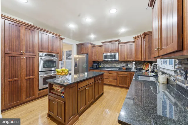 a kitchen with stainless steel appliances granite countertop a refrigerator a stove and a sink