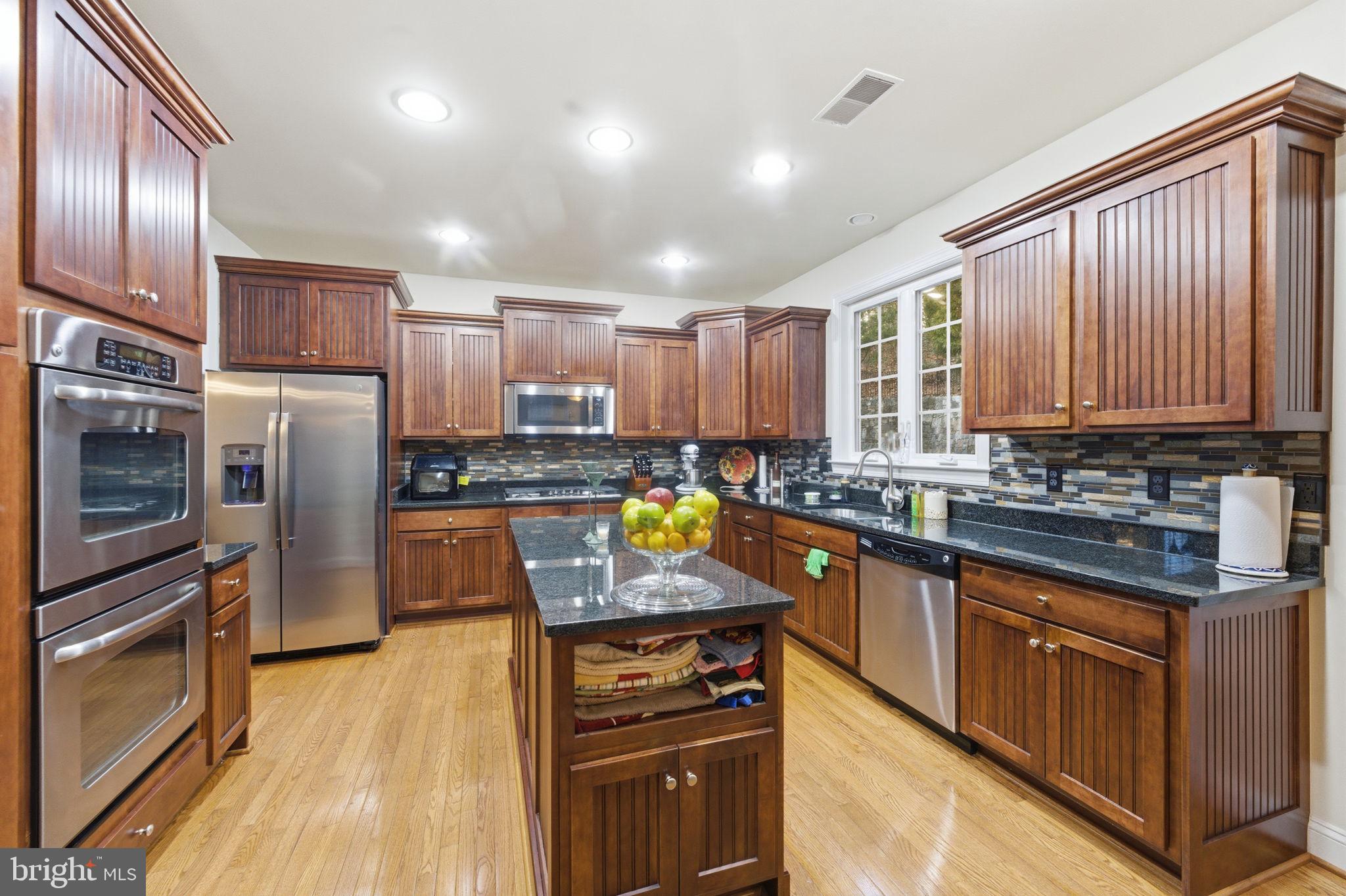 7669 Oak Field Court Springfield, VA 22153 - Photo 8 of 57 a kitchen with stainless steel appliances granite countertop a stove top oven a sink dishwasher a refrigerator and cabinets with wooden floor