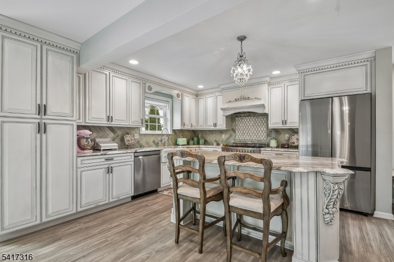 83 White Street Dover, NJ 07801 - Photo 3 of 26 a kitchen with kitchen island granite countertop wooden floors white cabinets and stainless steel appliances