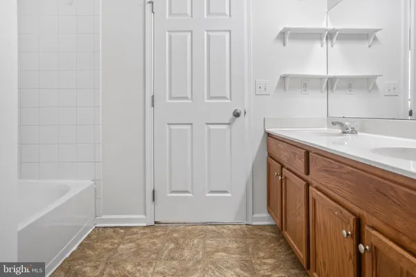 a bathroom with a granite countertop sink and mirror with bathtub