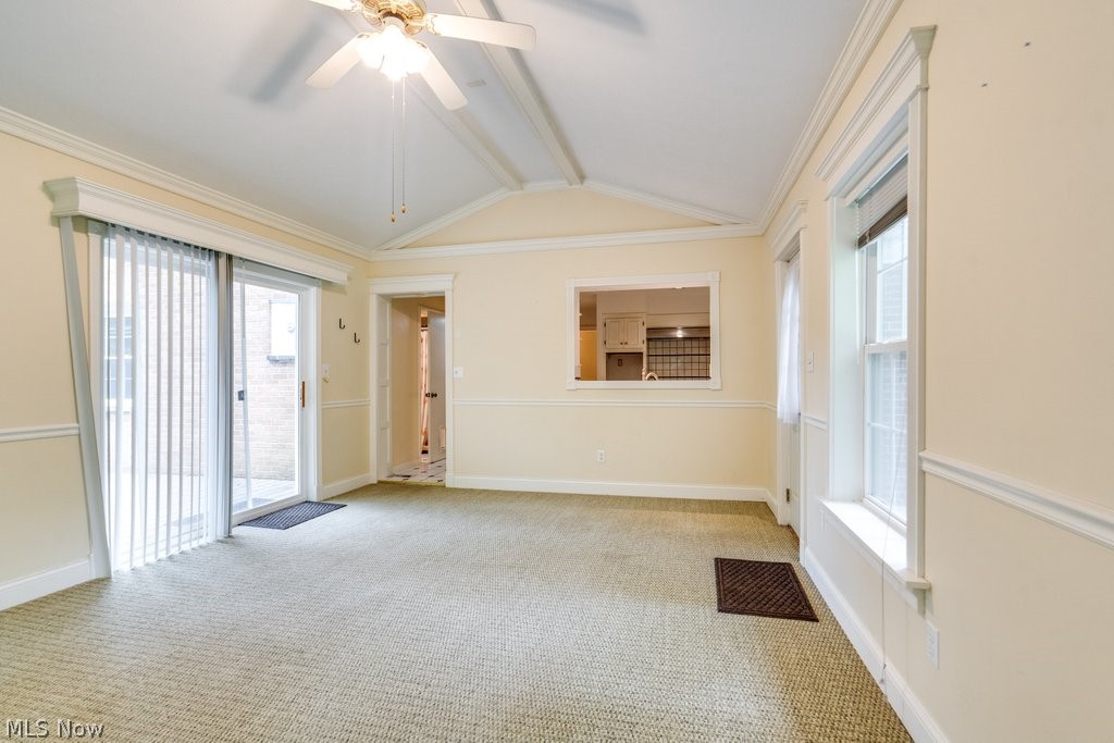 3060 Chamberlain Road Akron, OH 44333 - Photo 23 of 47 Carpeted spare room featuring a healthy amount of sunlight, vaulted ceiling with beams, ornamental molding, and ceiling fan
