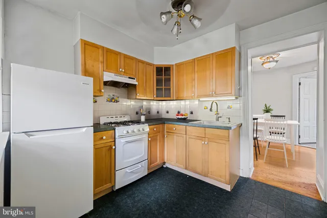 a kitchen with granite countertop a refrigerator a sink a stove and white cabinets