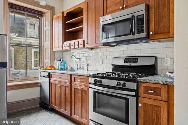 a kitchen with stainless steel appliances granite countertop white cabinets and a stove top oven