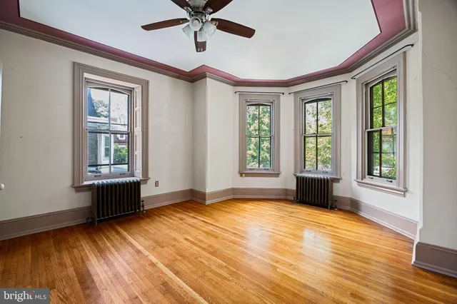 a view of an empty room with a window and wooden floor