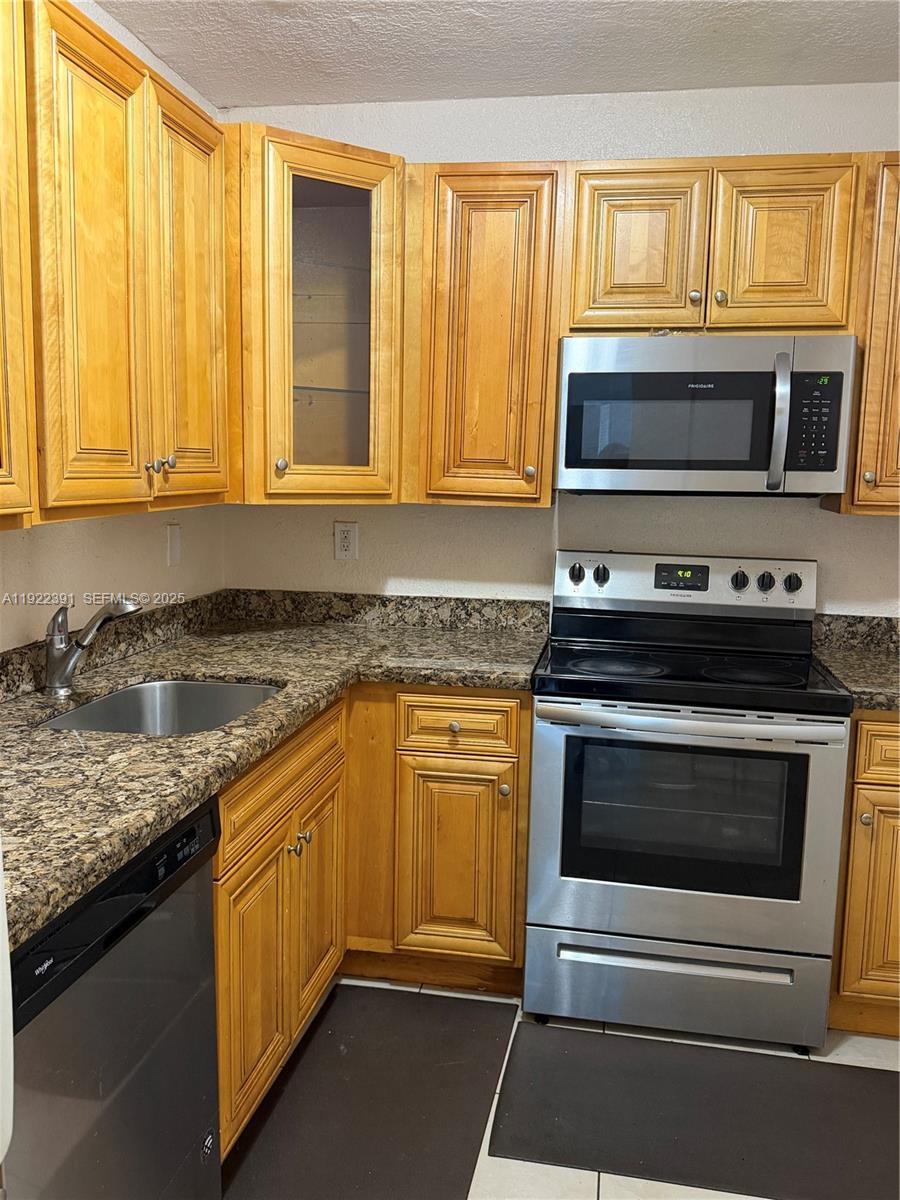 6701 Northwest 169th Street, Unit B301 Hialeah, FL 33015 - Photo 4 of 7 a kitchen with stainless steel appliances granite countertop a stove and a microwave