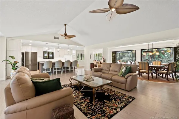 a living room with furniture a rug potted plant and a window